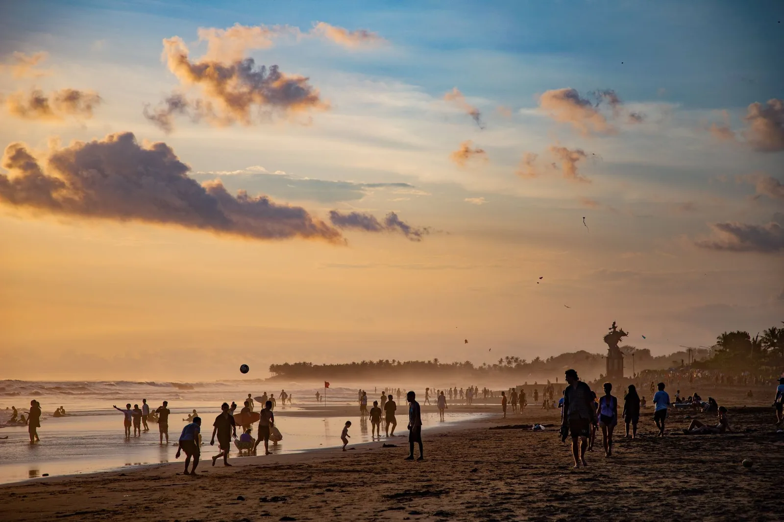 Coucher de soleil sur la plage de Canggu à Bali, avec des promeneurs sur le sable