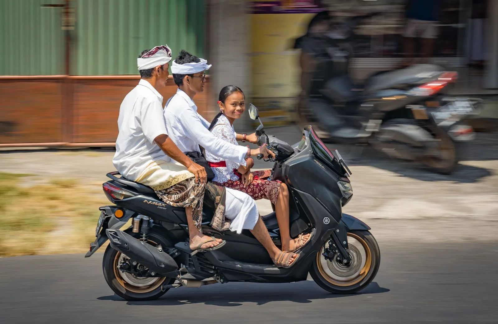 Famille balinaise en tenue traditionnelle circulant à scooter