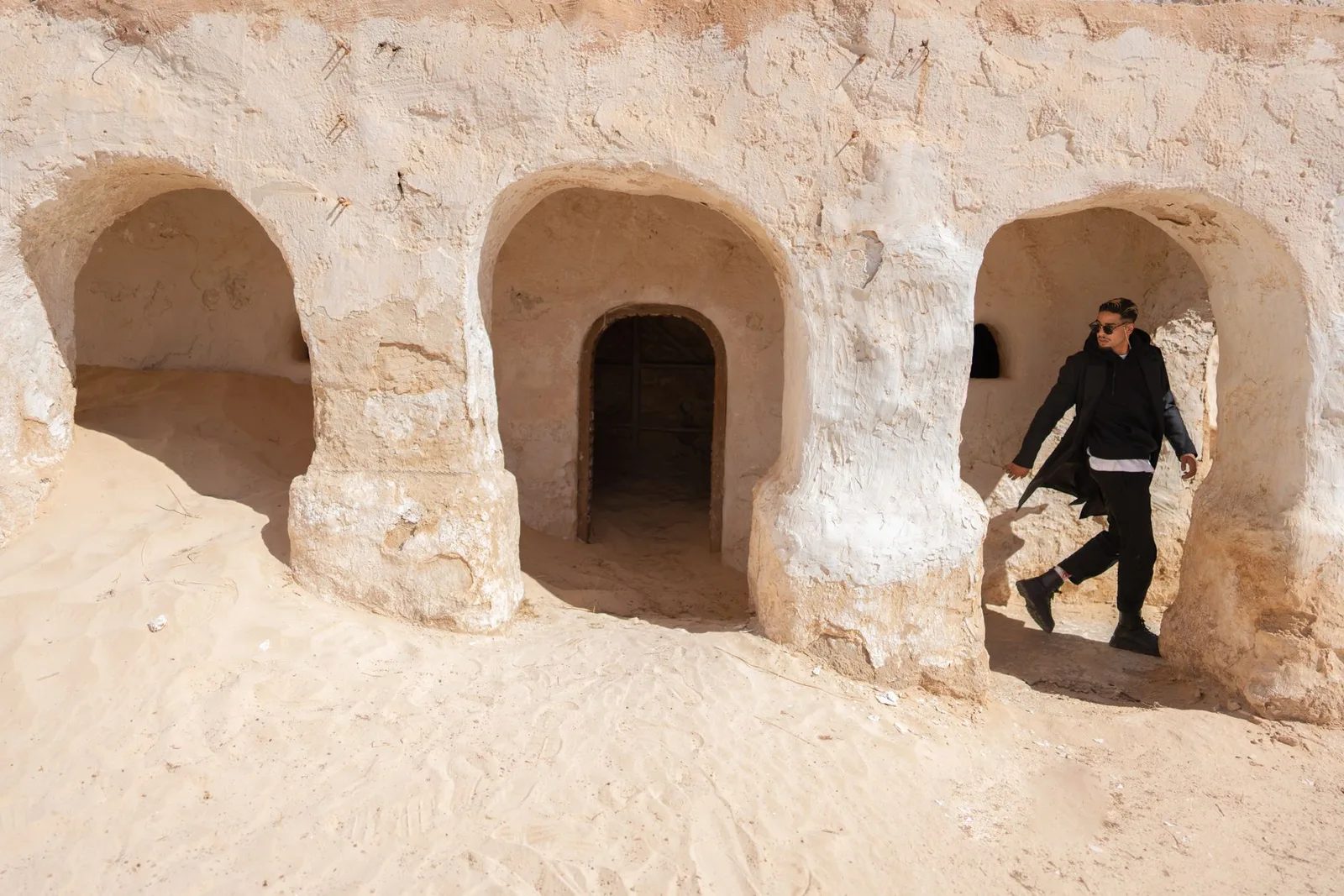 Marcheur devant d'anciennes habitations troglodytiques dans le paysage désertique de Tataouine