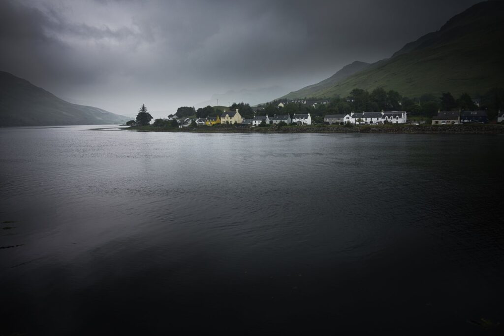 Village écossais au bord d'un loch sous un ciel nuageux