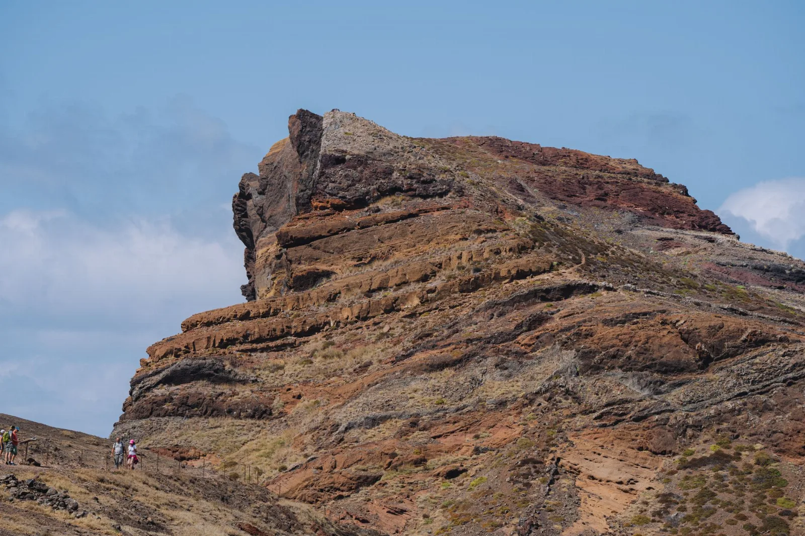 Arête rocheuse ocre du Cap-Vert parcourue par des randonneurs, végétation rase et ciel bleu