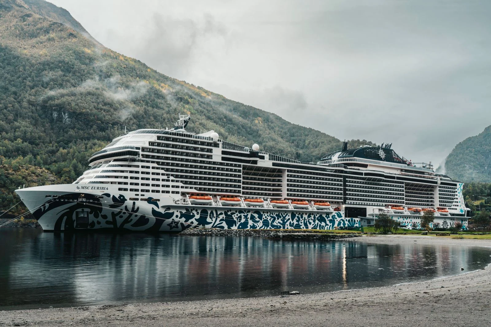 Navire de croisière à quai dans un fjord norvégien sous des nuages bas