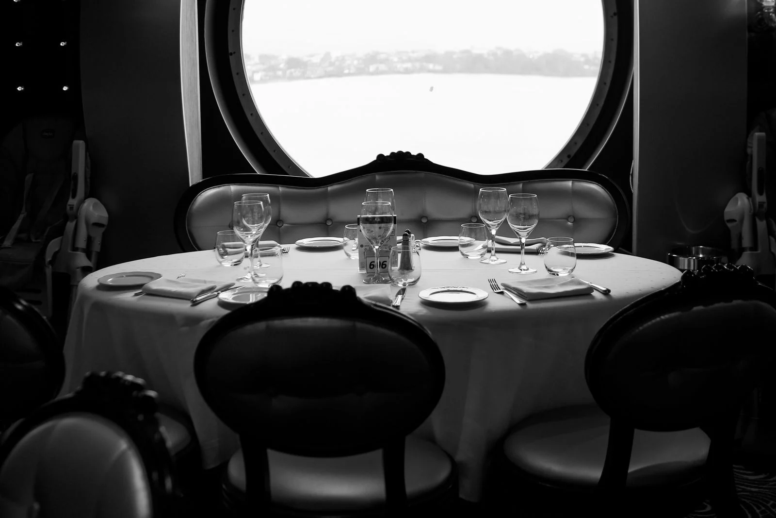 Table dressée dans le restaurant d'un navire, devant un hublot rond