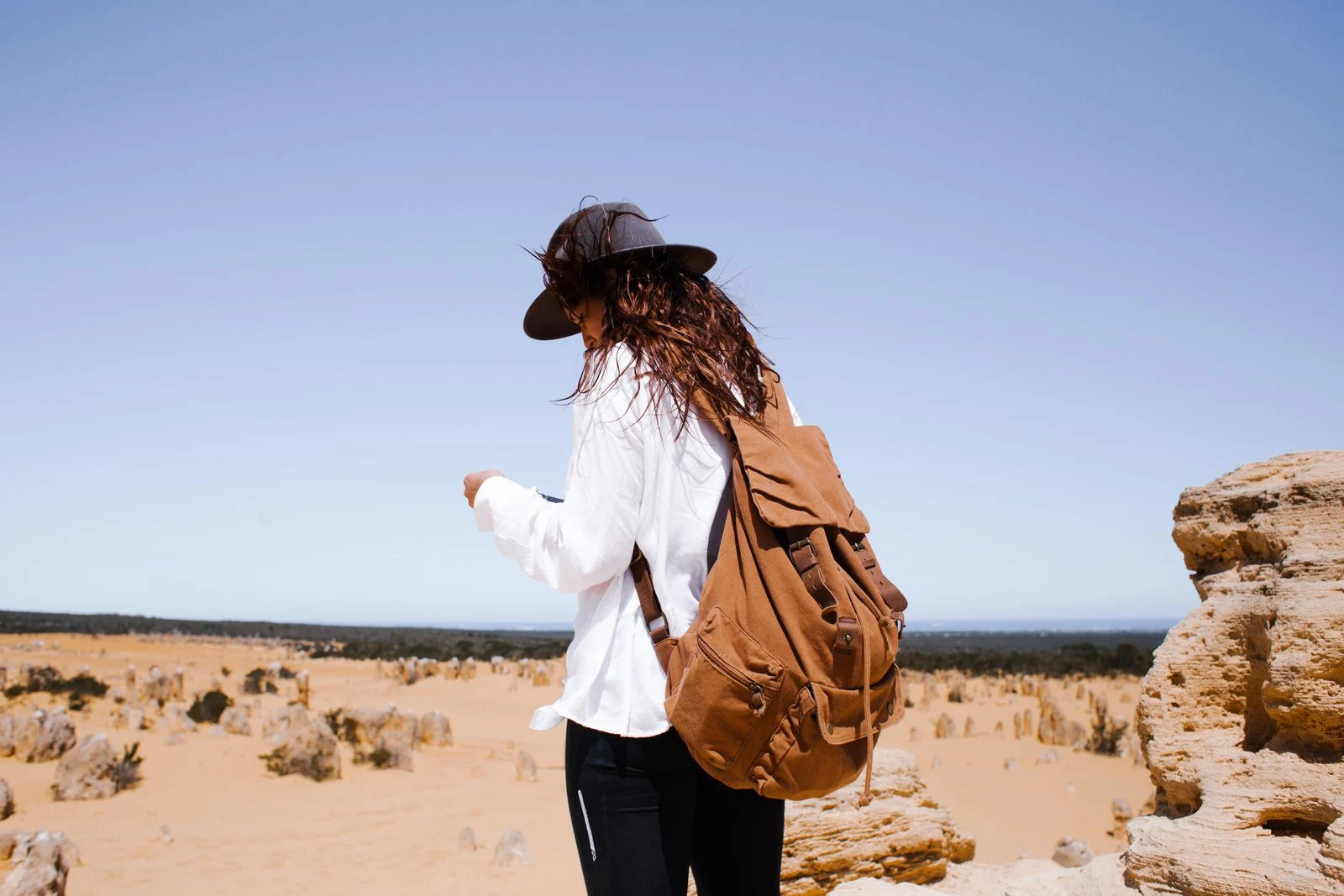 Voyageuse en chemise à manches longues et chapeau dans un paysage désertique