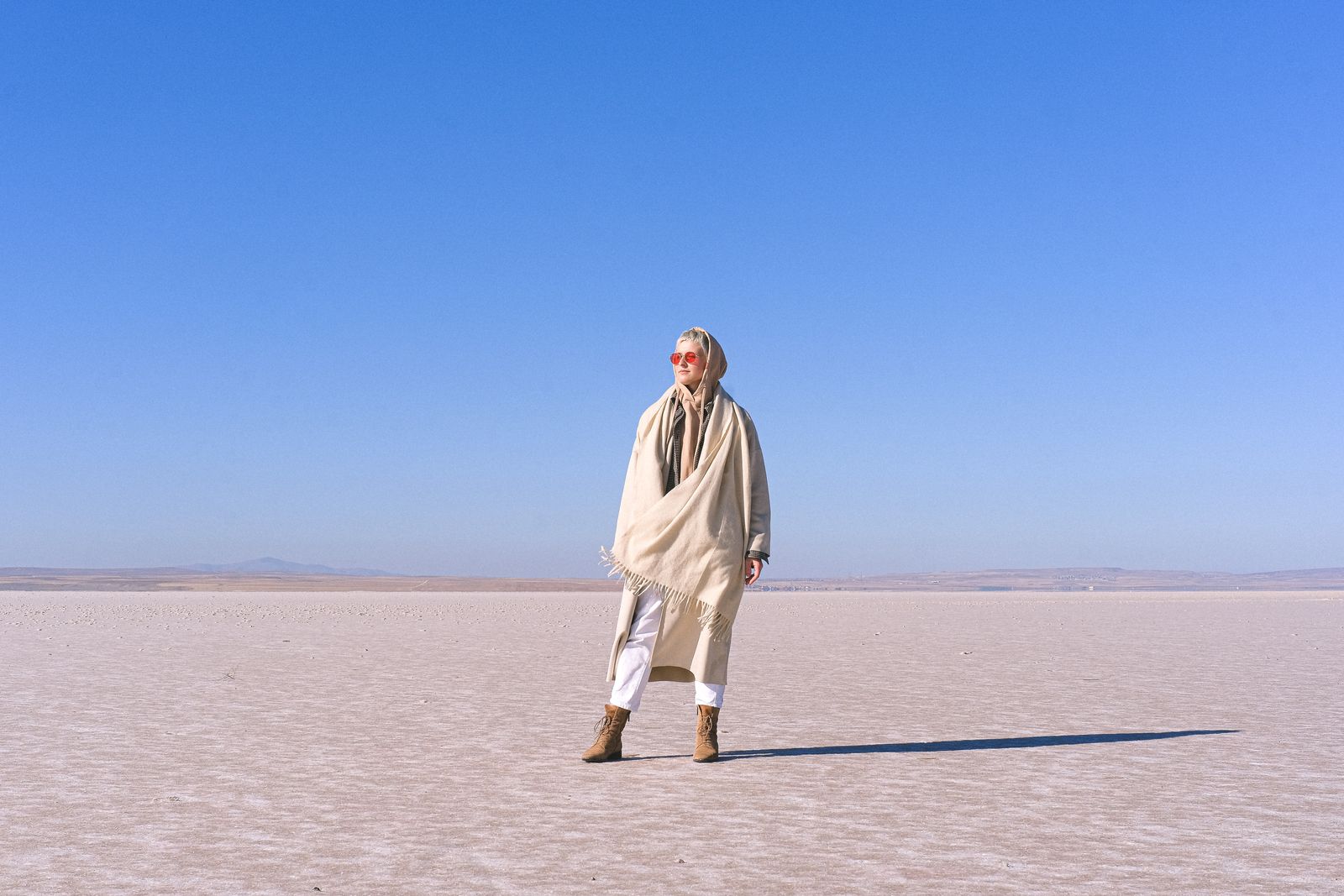Femme dans un paysage désertique, foulard noué sur la tête et lunettes de soleil