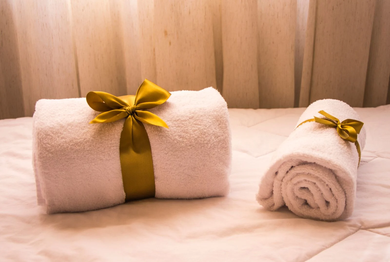 Serviettes de bain roulées et disposées sur un lit