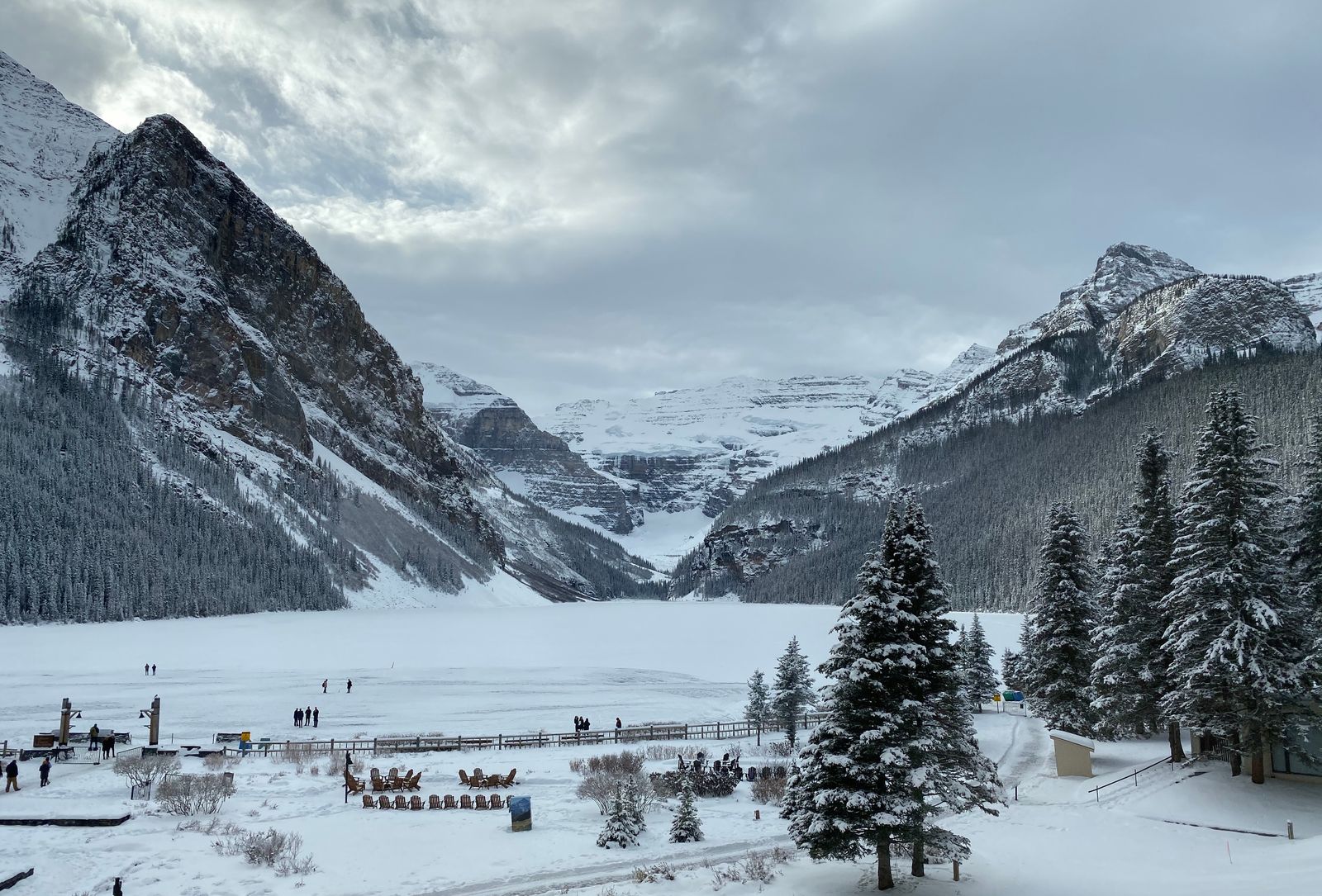 Lac Louise gelé et enneigé, des promeneurs sur la glace au pied des montagnes
