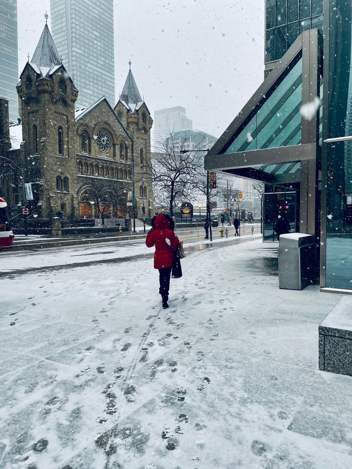 Passante en parka rouge à capuche sur un trottoir enneigé de Toronto