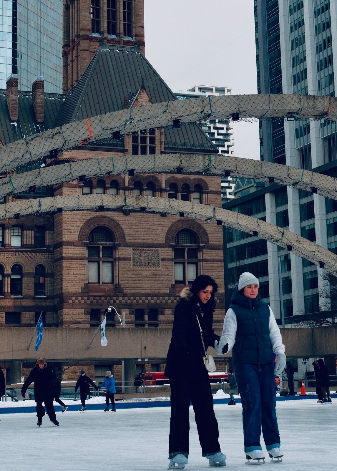 Deux personnes en tuque et manteau d'hiver sous les arches de Nathan Phillips Square, à Toronto