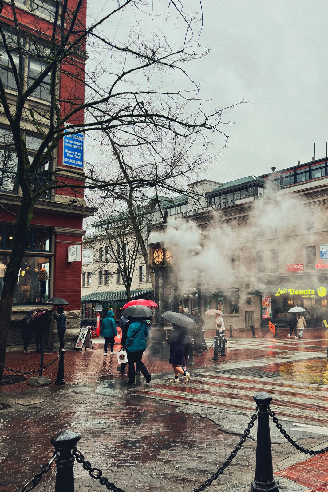 Passants sous des parapluies près de l'horloge à vapeur de Gastown, à Vancouver, un jour de pluie