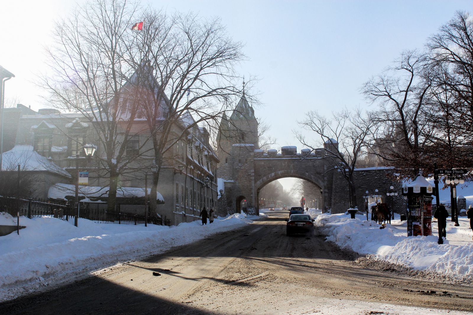 Rue enneigée du Vieux-Québec menant à une porte fortifiée en pierre