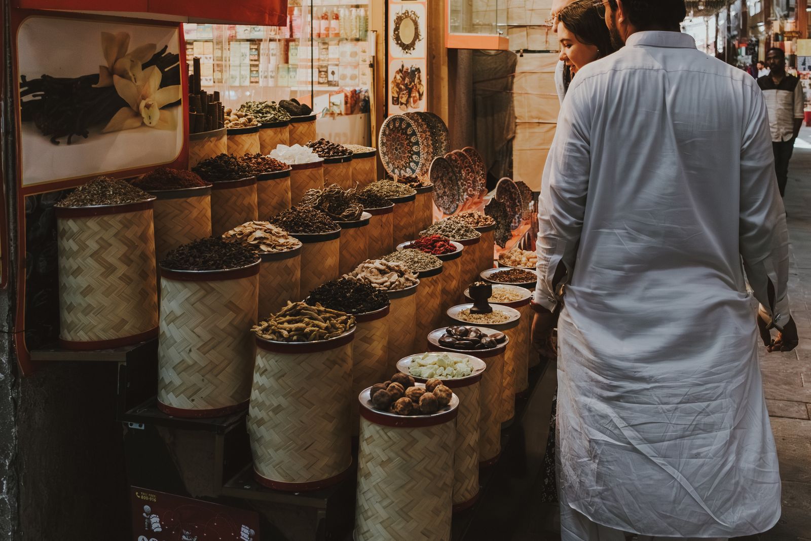 Paniers d'épices au souk de Dubaï, un homme en kandura blanche devant l'étal