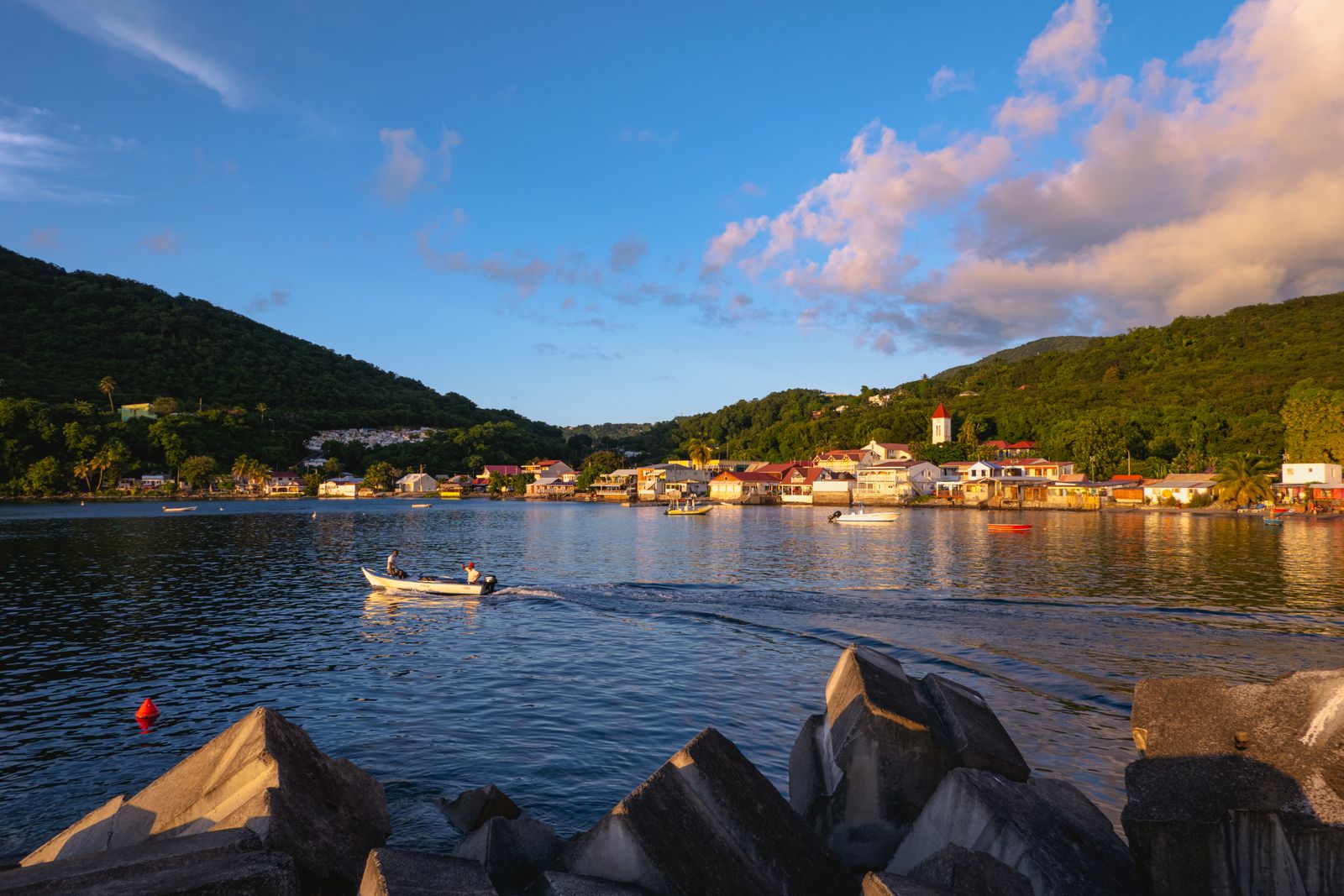 Baie de Deshaies en fin de journée, bateau au mouillage et village au pied des mornes boisés