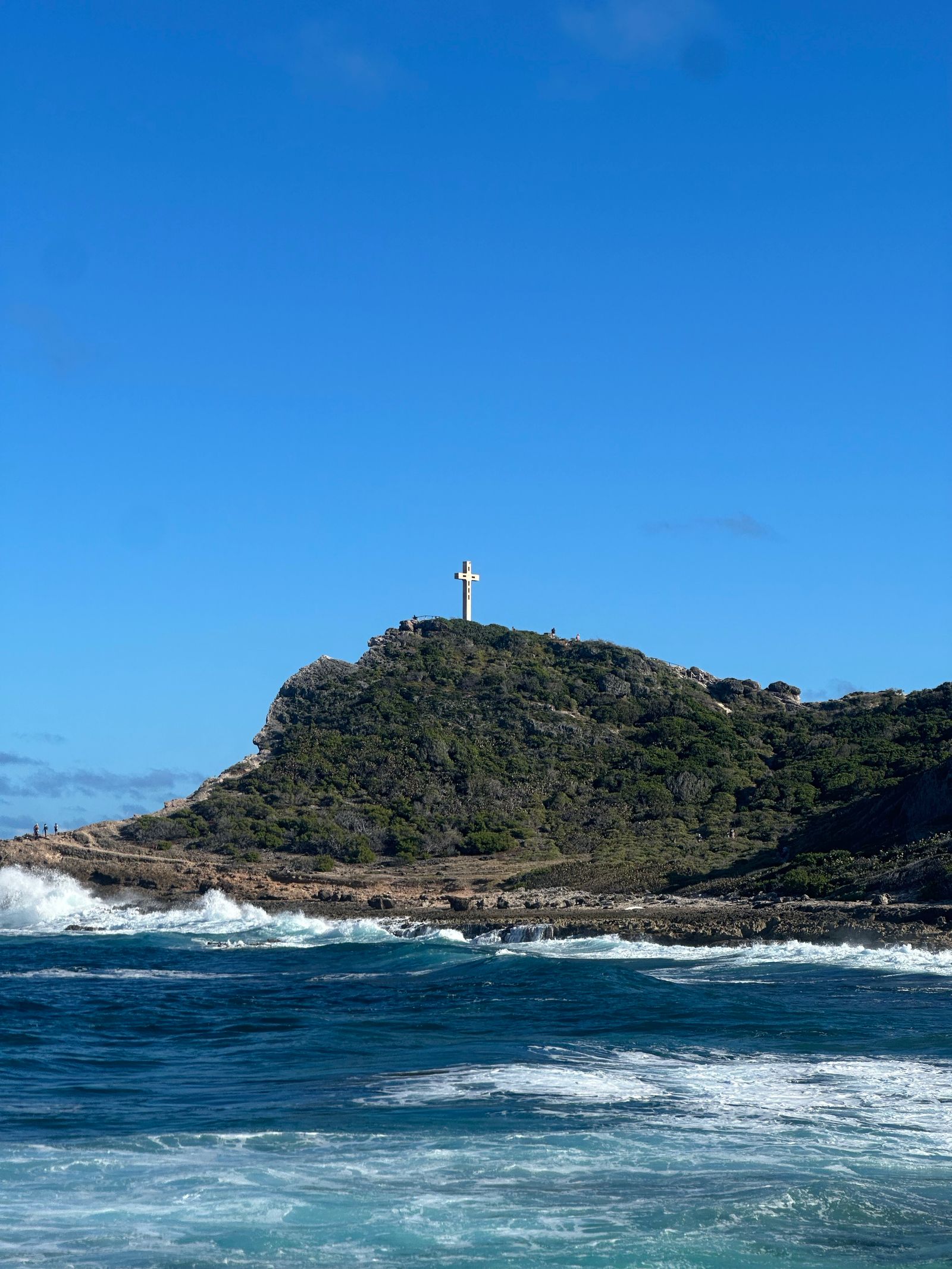 Promontoire rocheux de la pointe des Châteaux surmonté d'une croix, vagues sur les rochers