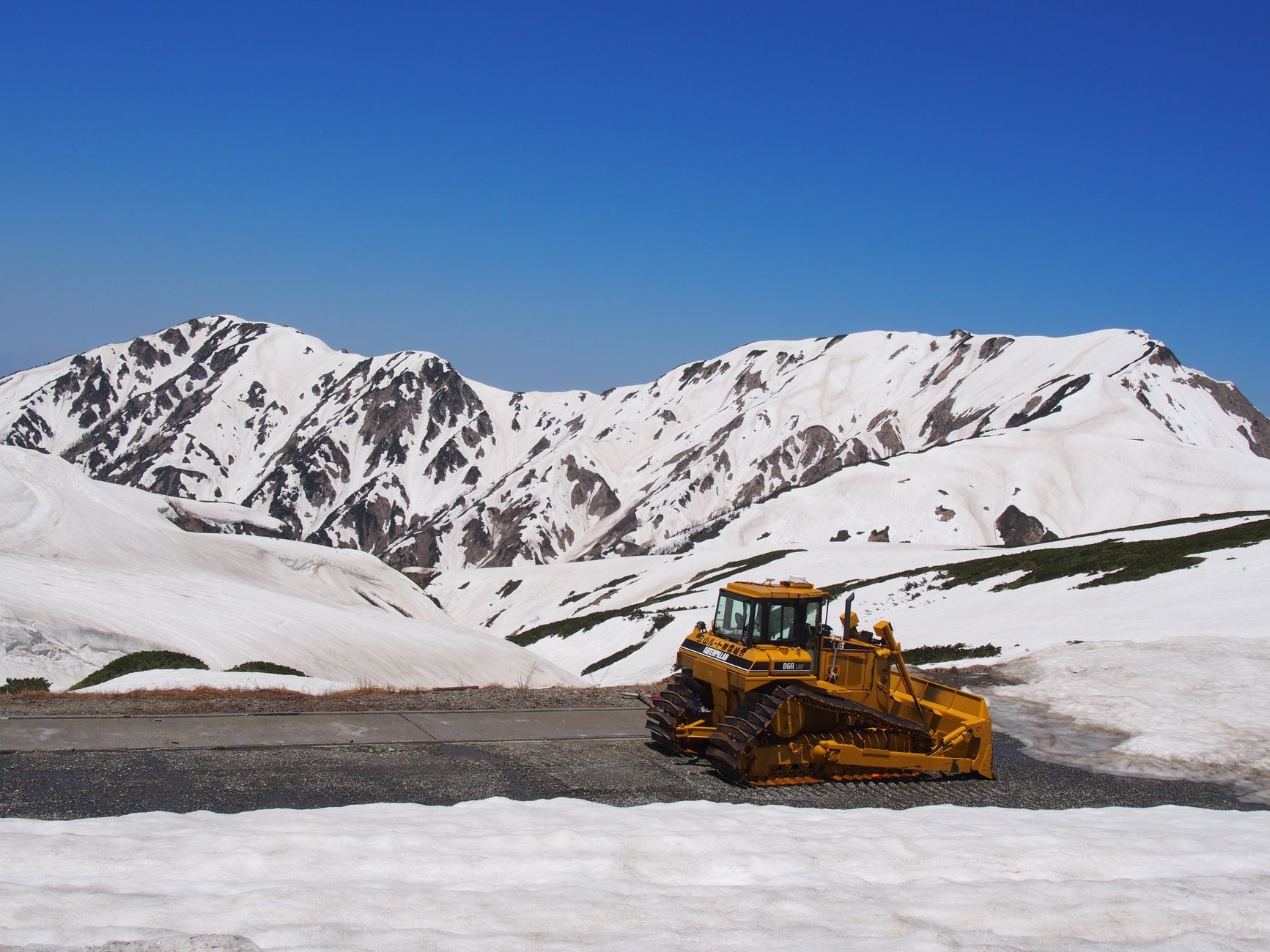 Un engin de déneigement dégage la route de Tateyama entre les congères de printemps