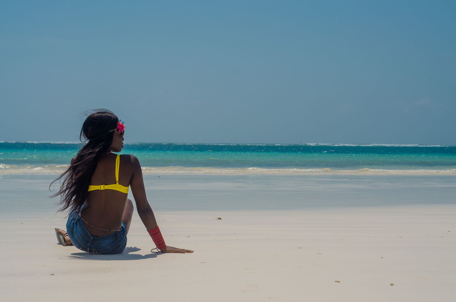 Femme assise sur le sable blanc de la plage de Diani, face à l'océan Indien