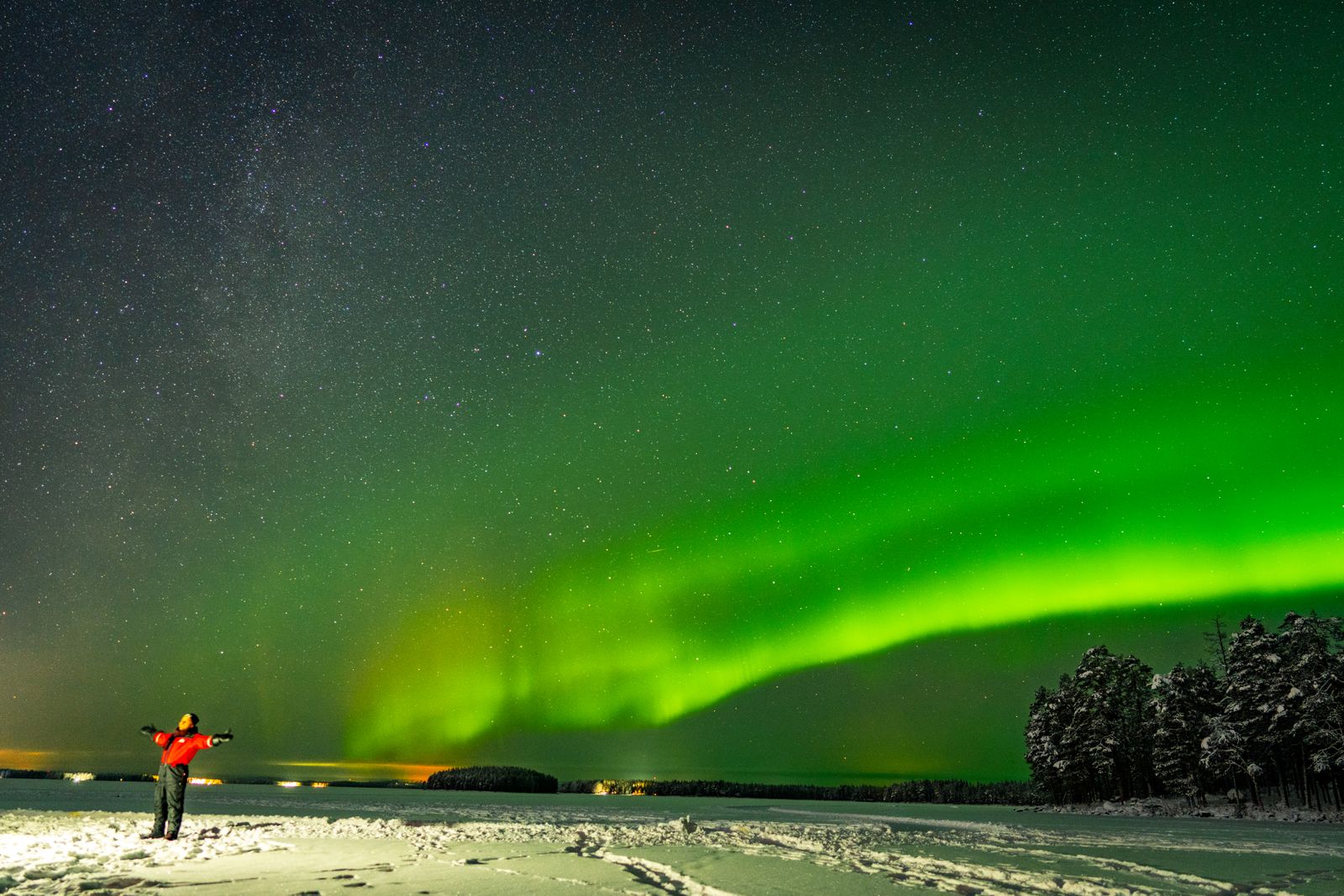 Aurore boréale verte au-dessus d'un paysage enneigé près de Rovaniemi, une personne debout au premier plan