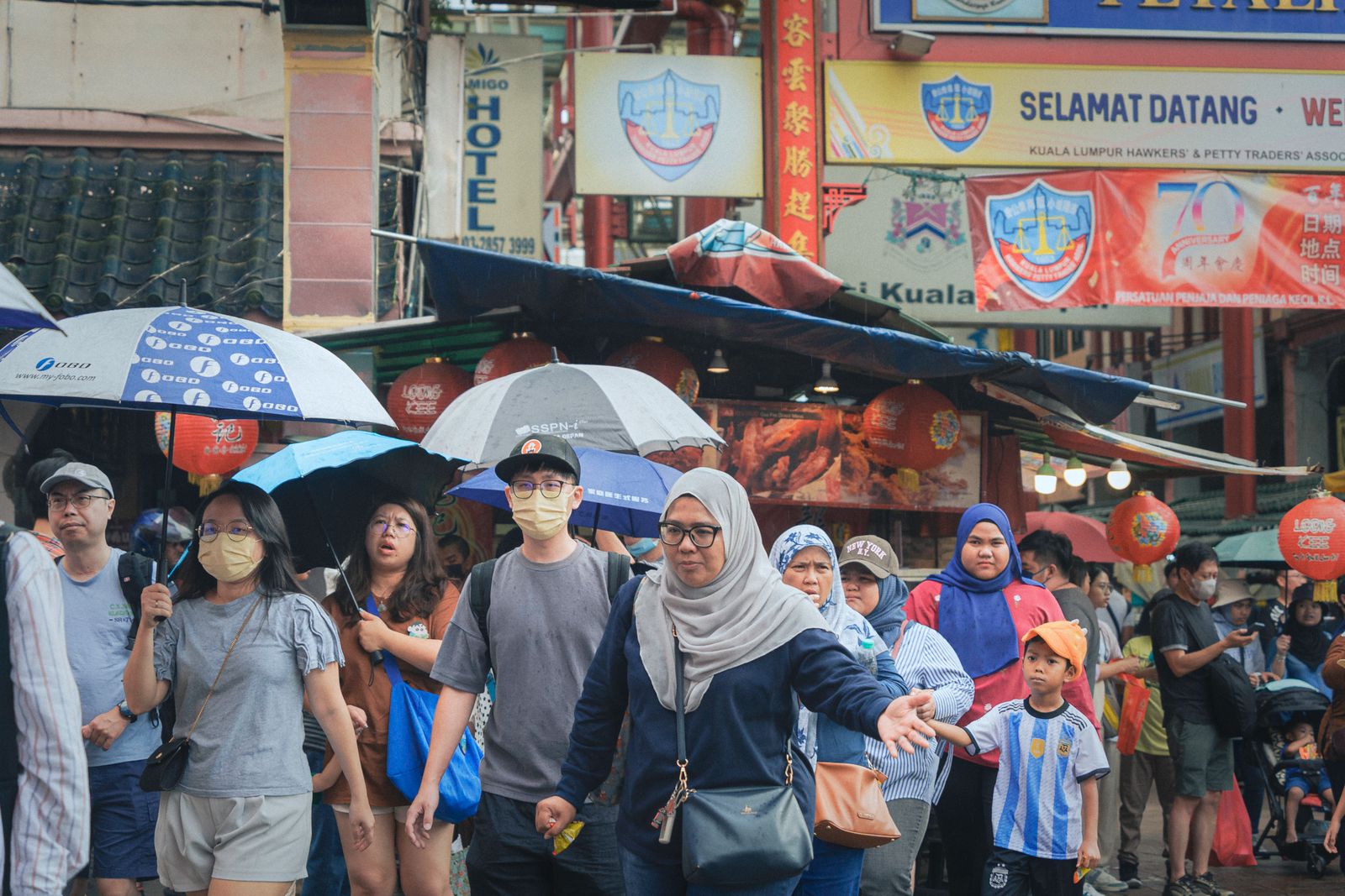Des passants sous des parapluies dans une rue de Chinatown, à Kuala Lumpur
