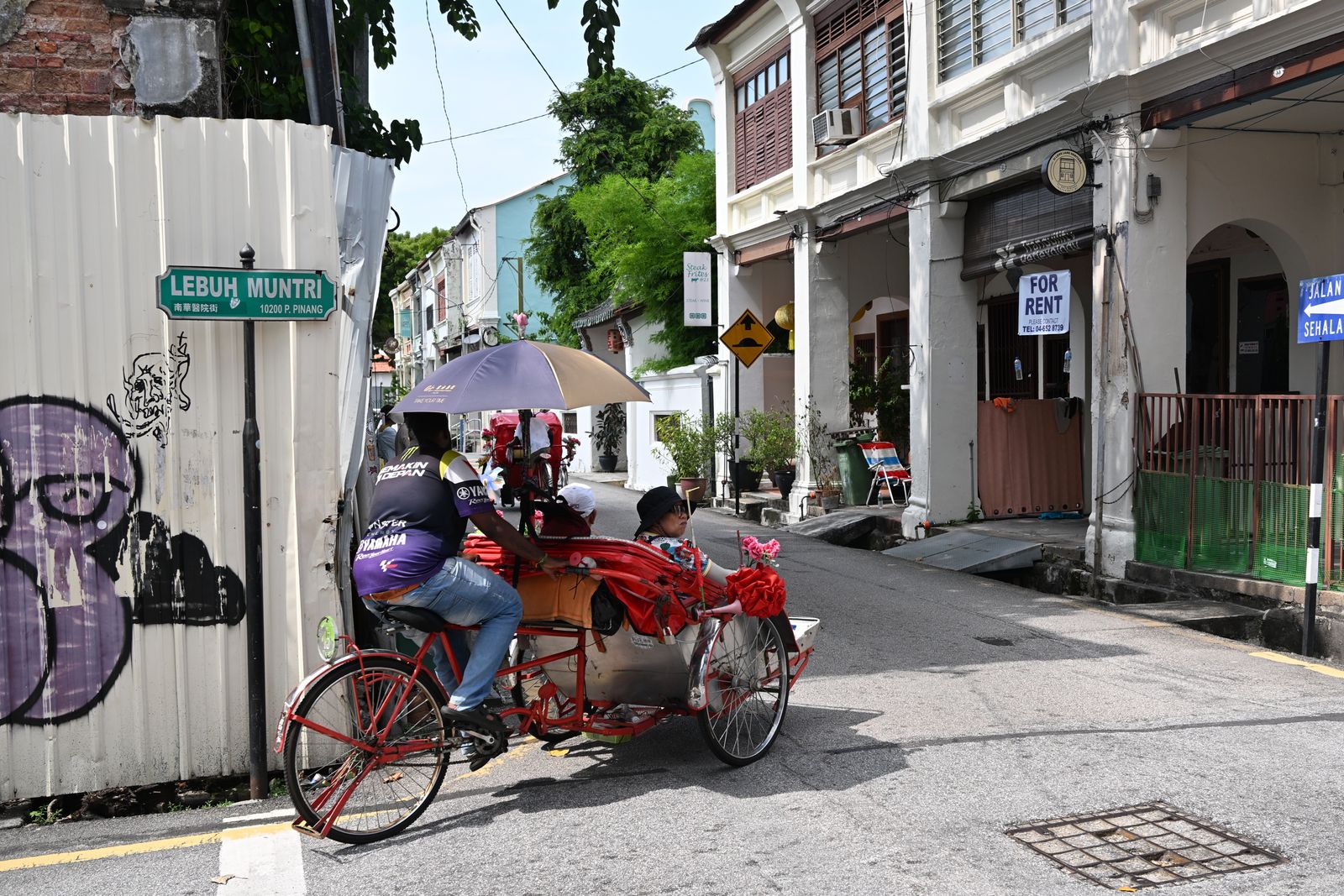 Un cyclo-pousse décoré de fleurs dans une rue de George Town, à Penang