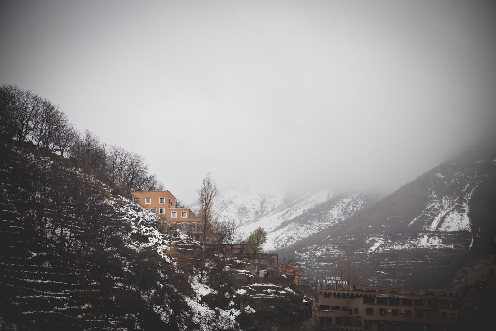 Versant boisé et village sous la neige à Imlil, sommets dans la brume