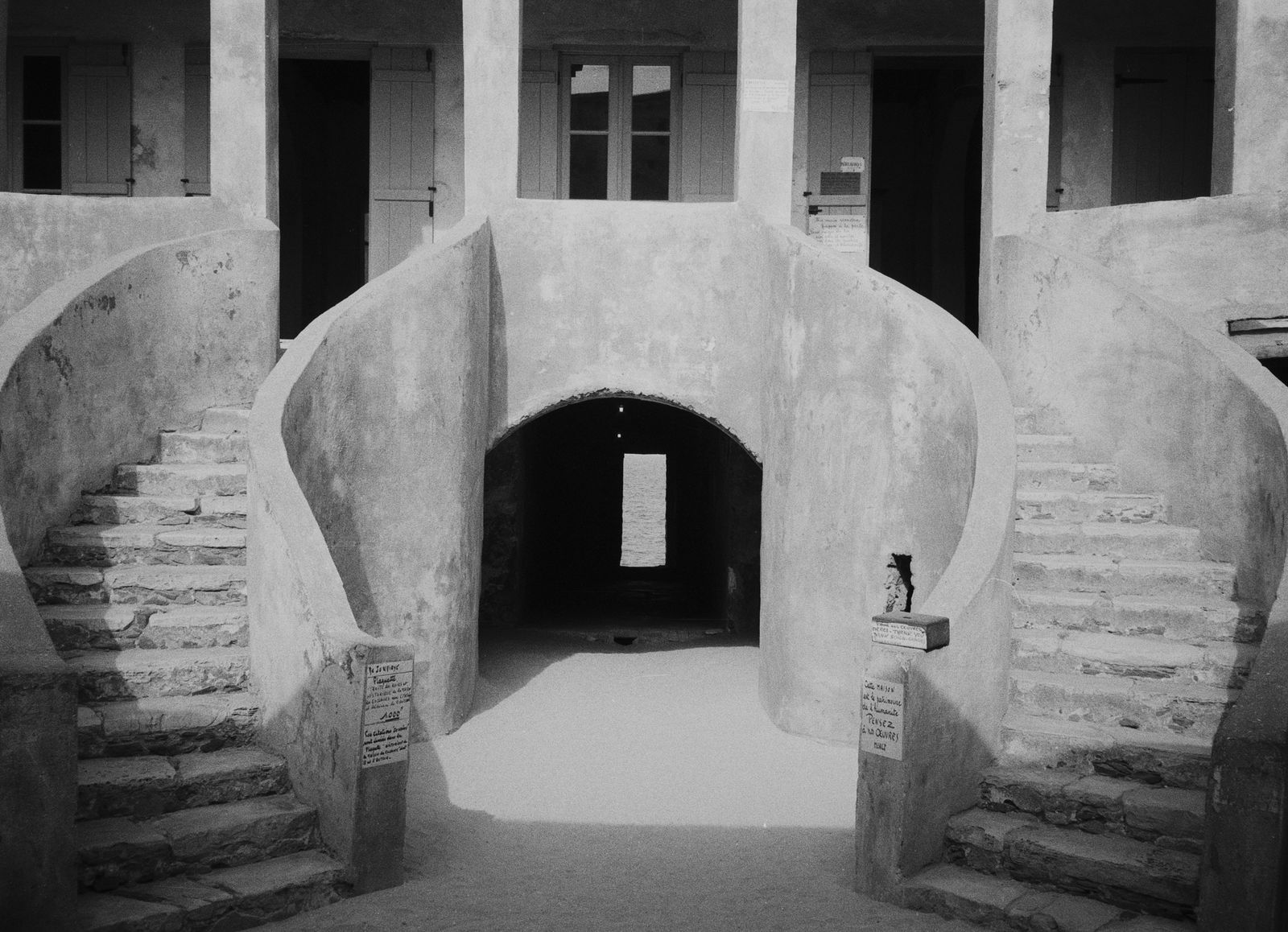 Escalier double en fer à cheval dans la cour d'une maison de Gorée, en noir et blanc