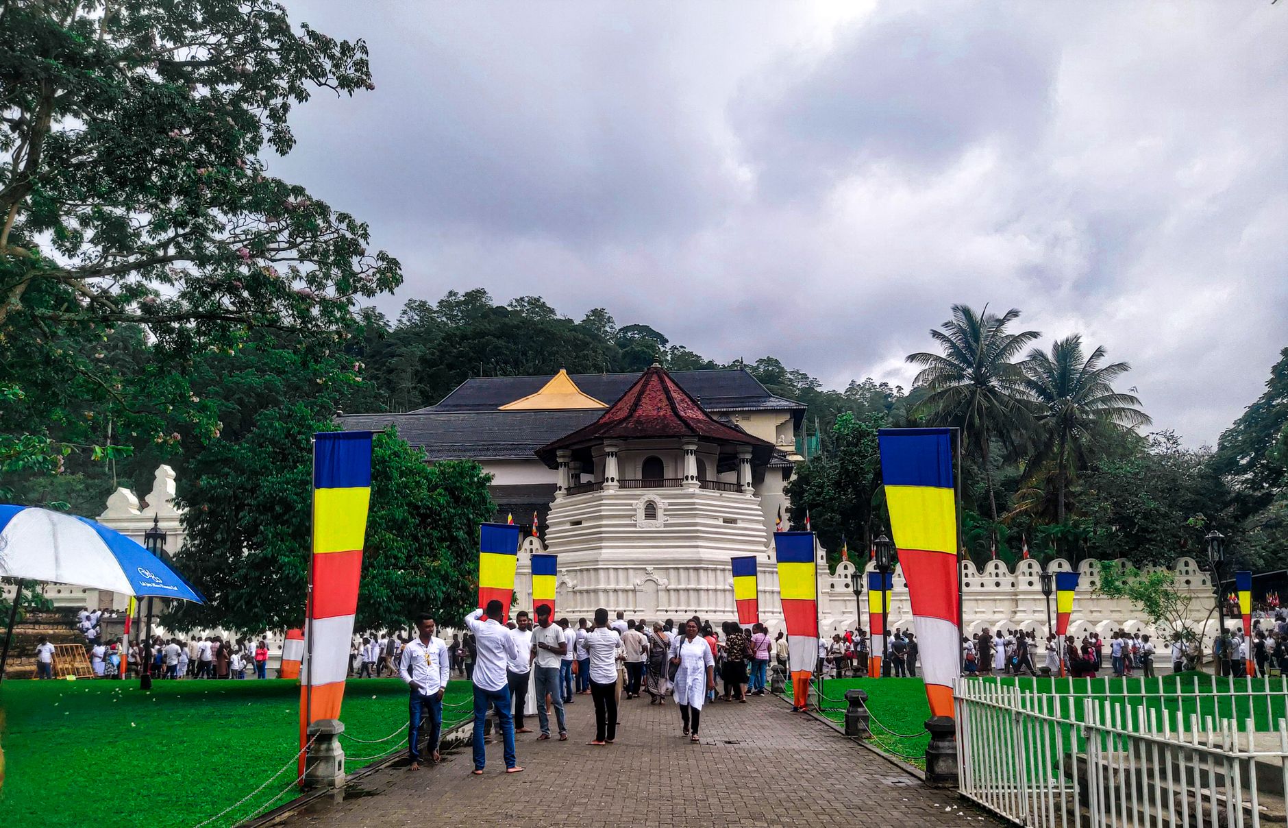 Des visiteurs devant le Temple de la Dent à Kandy, entre les drapeaux bouddhistes