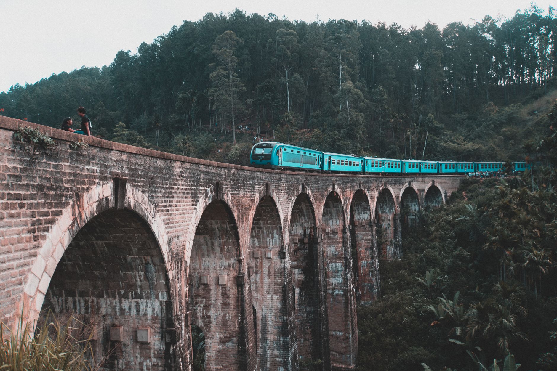 Un train bleu franchit le pont de Nine Arch à Ella, au milieu de la forêt