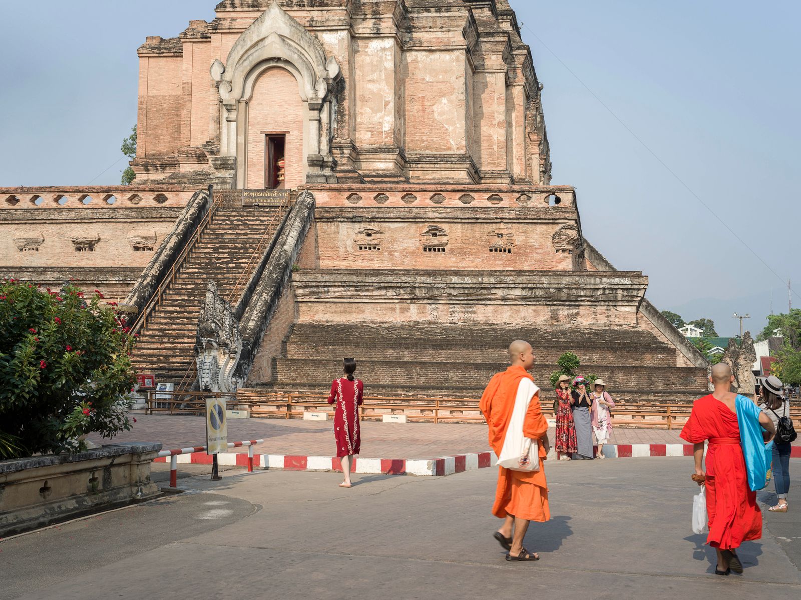 Moines en robe orange et visiteurs devant le Wat Chedi Luang, à Chiang Mai