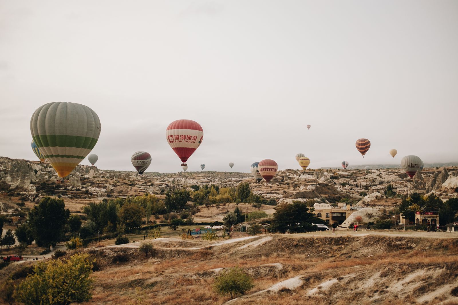 Des montgolfières au-dessus de la campagne sèche de Cappadoce, sous un ciel voilé