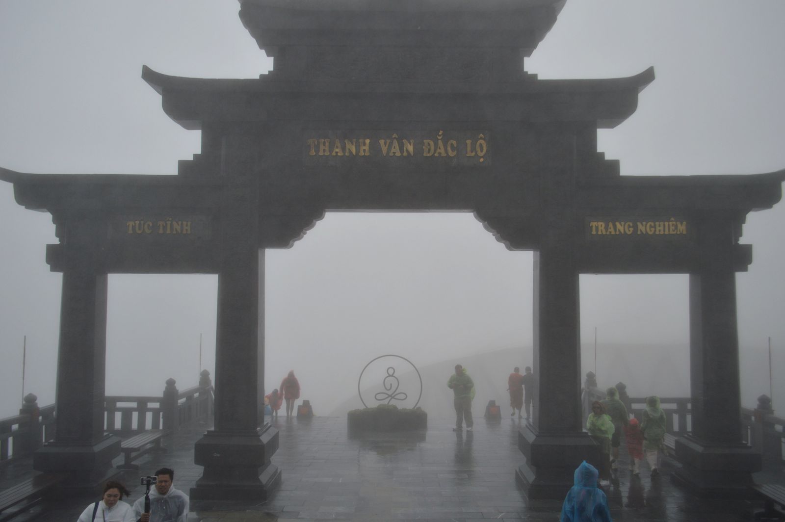 Visiteurs sous le grand portique du Fansipan, dans un brouillard épais