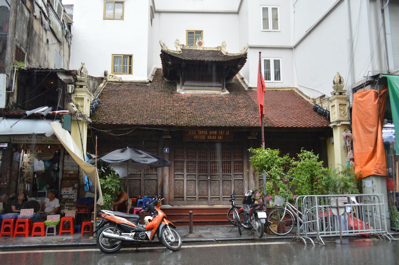 Bâtiment traditionnel à toit de tuiles au bord d'une rue de Hanoï, motos garées devant